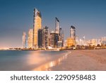 Small photo of Stunning sandy beach near Corniche seaside embankment with great night view of Abu Dhabi, UAE towering skyscrapers
