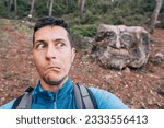 Small photo of man stands amidst a dense forest, wearing an expression of astonishment and awe. His eyes widen as he encounters a mystical troll emerging from the shadows.