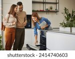 Female shop assistant helping young couple choose new electric stove