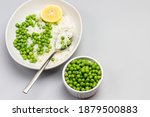 Boiled basmati rice with green peas in plate. Green peas in bowl. Copy space. Grey background. Flat lay