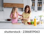 Small photo of A friendly family from smiling mother with daughter manage in the kitchen in a playful manner and joyful mood. A young woman mom and little girl prepares to make sandwiches together. The concept of