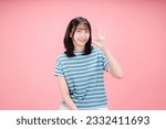 Small photo of Very good. Smiling asian woman showing okay with satisfied face, praise and compliment great job, standing over pink background