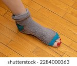Small photo of Old tacky sock completely torn apart with foot toes peeking out
