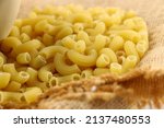 Small photo of Close up shot of scattered macaroni on a gunny sack. Very detail looks of macaroni. Yellowish colour macaroni made in Italy