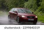 Small photo of Stony Stratford,Bucks,UK - May 6th 2023. 2004 red AUDI A3 driving in the rain on a wet road