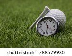 Golf time with golf ball and clock on green grass.