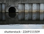 Small photo of Culvert Opening in Pond Daylight Water Reflection
