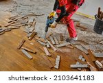 Small photo of Parquet in wood glued to the slab, removed with an electric demolition hammer by a craftsman in workwear, in the apartment under renovation. In the foreground, the removed parquet slats.