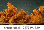 Small photo of Freeze Motion Shot of Flying Fresh Fried Chicken Wings or Strips, Close-up