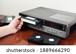 Small photo of VHS videocassette is put into the video recorder to watch the video, another video cassette is on the video-tape recorder
