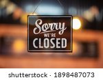 Sorry we're closed sign. grunge image hanging on a glass door.