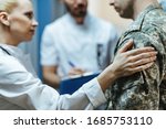 Close-up of a soldier being consoled by healthcare workers at clinic. 