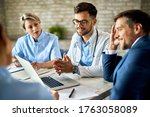 Group of healthcare workers and businessman using laptop while having a meeting in the office. Focus is on young doctor. 