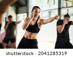 Female martial artist practicing punches while having exercise class at health club.