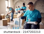 Small photo of Happy man in wheelchair working as volunteer at charitable community.