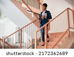 African American businesswoman holding digital tablet while walking down the stairs at work. Copy space.