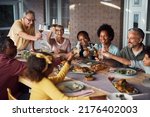Happy multiracial extended family toasting and having fun together during meal on a patio.