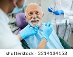 Happy mature man during teeth check-up at dental clinic.