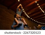 Happy father carrying his son on his shoulders while turning on the lightbulb on a patio.