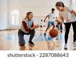 Small photo of Happy PE teacher encouraging her student during basketball practice at school gym.