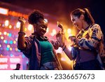 Small photo of Happy African American woman and her female friend having fun and dancing while attending open air music concert at night.