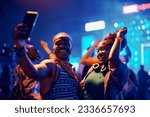 Happy African American couple dancing and taking selfie with cell phone during summer music festival. 