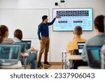 Male teacher using interactive whiteboard while giving a lesson to high school students in the classroom.