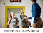 Small photo of Happy mother with teenage daughter greeting high school principal in a hallway.