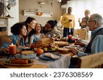 Happy multiracial parents and their kids laughing during family meal on Thanksgiving in dining room. 