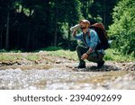Small photo of Young backpacker refreshing himself with fresh mountain creek water. Copy space.
