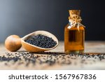 Small photo of glass bottle of black cumin seeds essential oil , Nigella Sativa in spoon on wooden background. Organic herbal medicine for many diseases, black cumin