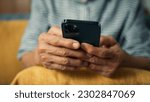 Small photo of Beautiful elderly woman smile using mobile phone enjoy playing social media checking email. Happy attractive grandma hand holding smartphone scrolling looking at screen sit on sofa in living room