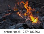 Small photo of Fire is burning a pile of wooden logs in a bonfire. The logs have now turned into charcoal.