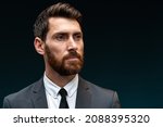 Small photo of Portrait of attentive self confident bearded man looking away with serious expression, unsmiling determined business man. Indoor studio shot isolated on black background