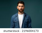 Small photo of Portrait of attentive self confident bearded man looking at camera with serious expression, unsmiling determined business man. Indoor studio shot isolated on blue background