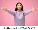 Small photo of Openhearted generous woman outstretching hands looking at camera with kind smile, greeting and regaling, happy glad to see you. Indoor studio shot isolated on pink background