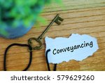 Small photo of Key and torn paper with text conveyancing on wooden background