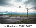 Small photo of Commerce City, Colorado, United States - 5.25.2023: Rocky Mountain Arsenal National Wildlife Refuge. The Great Plains. Front Range mountains in the distance. Long and empty road, utility poles.