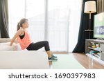 Small photo of Video streaming Stay home.home fitness workout class live streaming online.Asian woman doing strength training cardio aerobic dance exercises watching videos in the living room at home.Covid-19.