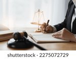Small photo of Asian female lawyer or legal advisor working on the scale of justice sitting at her desk and holding a pen to look at the information Detailed content about the scale of jurisprudence to study.