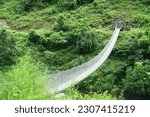 Small photo of A suspension bridge gracefully complements the lush Himalayan rainforest on the Manaslu Circuit trek in Nepal, offering a picturesque view from above.