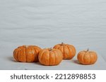 Four Small Pumpkins On A White...