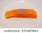 Small photo of Freshly Thawed Skinless Salmon Fillet: a raw, skinless salmon fillet arranged on a white pan, freshly thawed and ready to be prepared