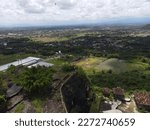 bantul yogyakarta,indonesia,maret 4 2023.

a hill that presents a beautiful view of the sky,
 among the green of nature stands houses and
 buildings in the distance.

aerial view dji mavic air 2.