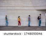 Small photo of Group of young people waiting for going inside a shop market while keeping social distance in a line during coronavirus time - City outbreak lifestyle, protective face mask and spread virus prevention