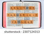 Small photo of Vancouver, BC, Canada - Circa May 2023: Scrabble letters spelling Bible Verse Galatians 5:22 Fruit of the spirit is Love