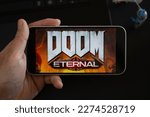 Small photo of Hand holding a gaming mouse with the Doom Eternal logo, surrounded by keyboard and mousepad. Addicted to this highly acclaimed FPS game from id Software.