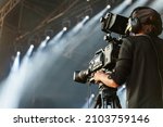 Professional camerawoman broadcasting live concert on camcorder.