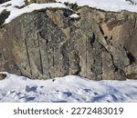Granite rocks under a snow cover with traces of industrial stone cutters