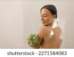 Attractive young woman with long hair does anti-cellulite massage with soft massage washcloth for the body and legs. Close-up of slender figure. Cosmetology and healthy body care.